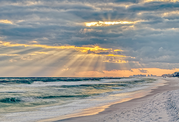 Dramatic pastel light sunset with sun rays in Santa Rosa Beach, Florida with Pensacola coastline coast cityscape skyline in panhandle and ocean